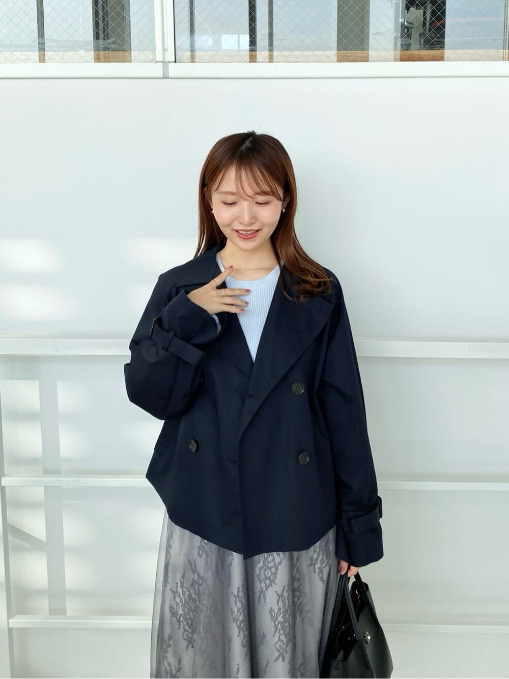 ブルー系のトレンチコート、ブルー系のワンピース、ブラック系のトートバッグを着用したレディースの冬コーディネートの8枚目の写真