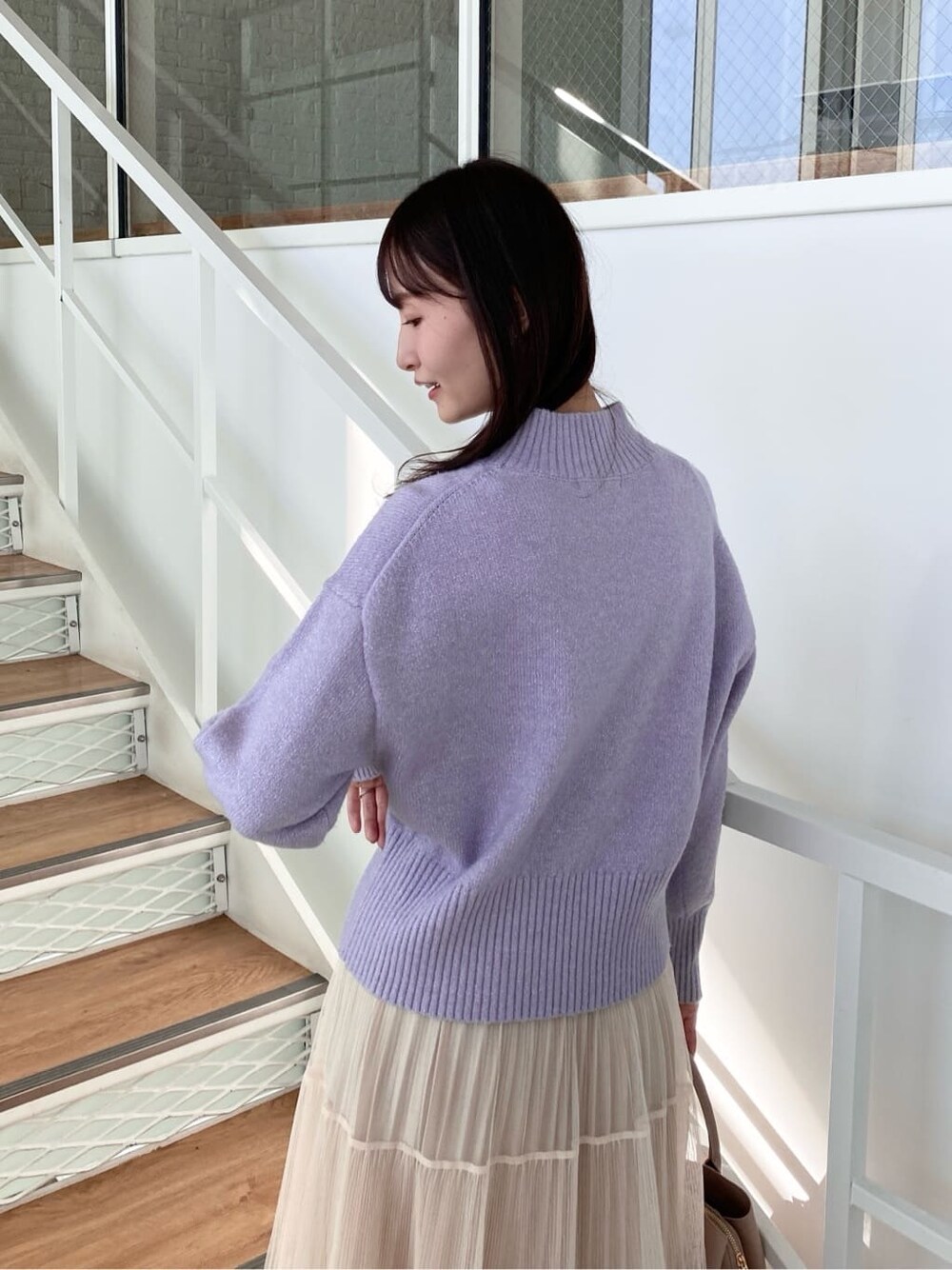 パープル系のニット/セーター、ベージュ系のスカート、ベージュ系のボストンバッグを着用したレディースの冬コーディネートの7枚目の写真