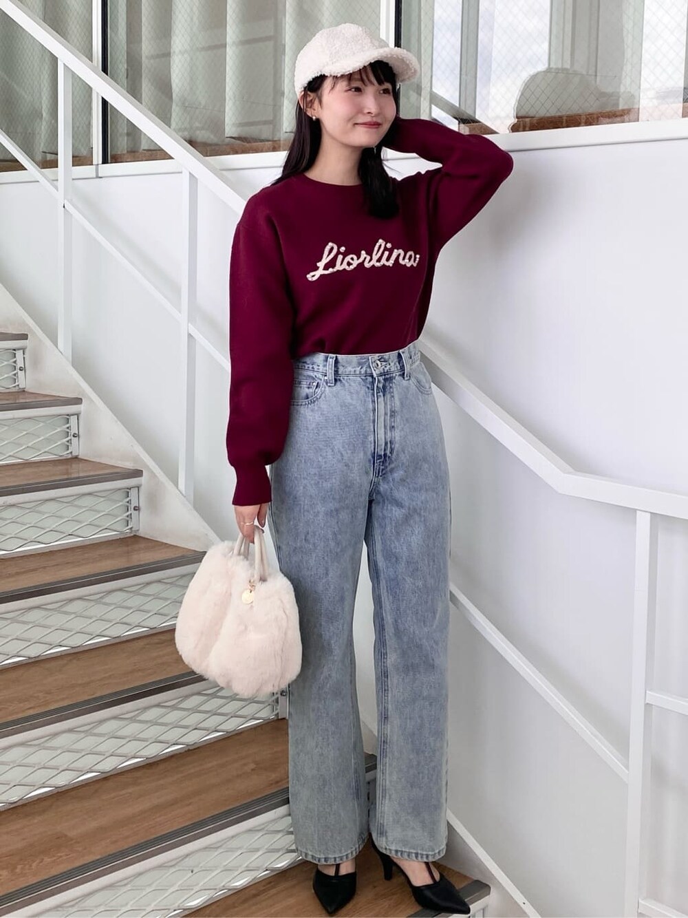 レッド系のニット/セーター、ブラック系のデニムパンツ、ホワイト系のショルダーバッグを着用したレディースの冬コーディネートの3枚目の写真