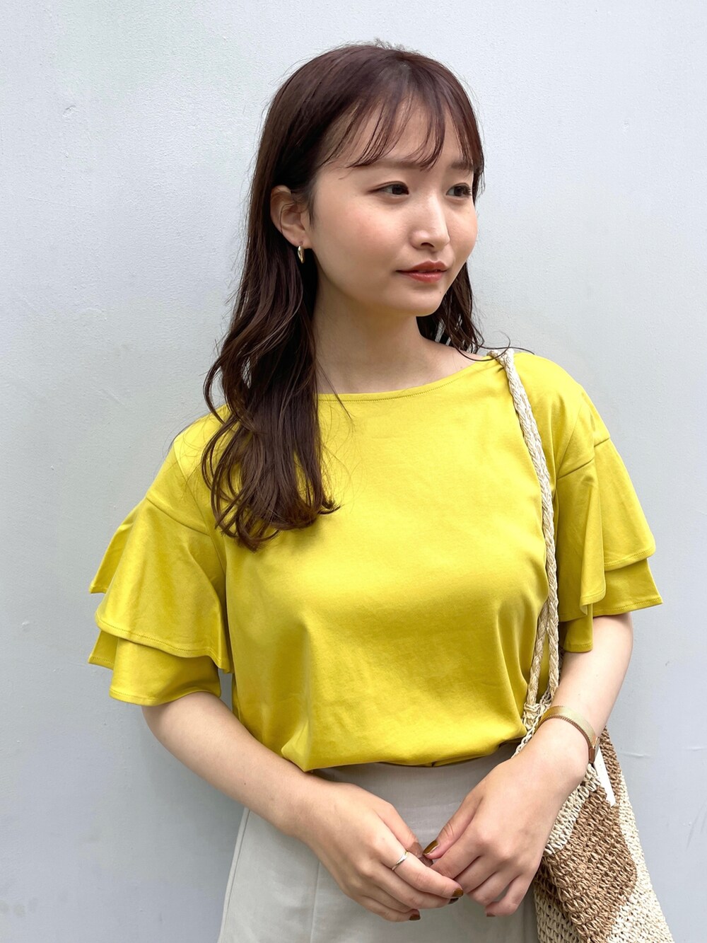 イエロー系のTシャツ/カットソー、グレー系のスカート、ベージュ系のサンダルを着用したレディースの春コーディネートの2枚目の写真