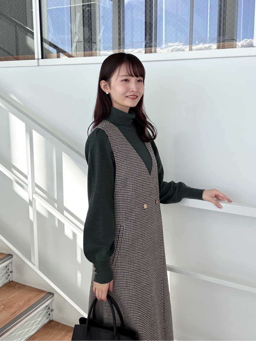 ブラウン系のワンピース、グリーン系のニット/セーター、ブラック系のボストンバッグを着用したレディースの冬コーディネートの8枚目の写真