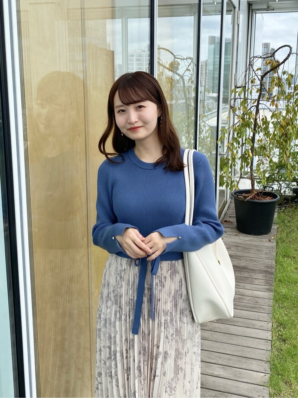 ブルー系のワンピース、ホワイト系のトートバッグ、ブラック系のパンプスを着用したレディースの秋コーディネートの6枚目の写真