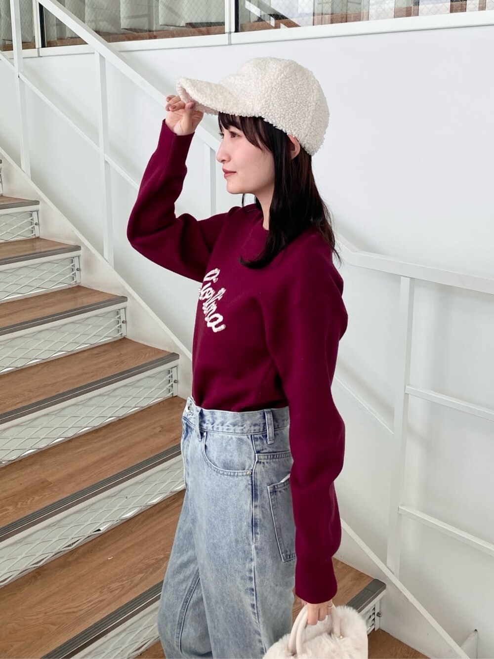 レッド系のニット/セーター、ブラック系のデニムパンツ、ホワイト系のショルダーバッグを着用したレディースの冬コーディネートの7枚目の写真