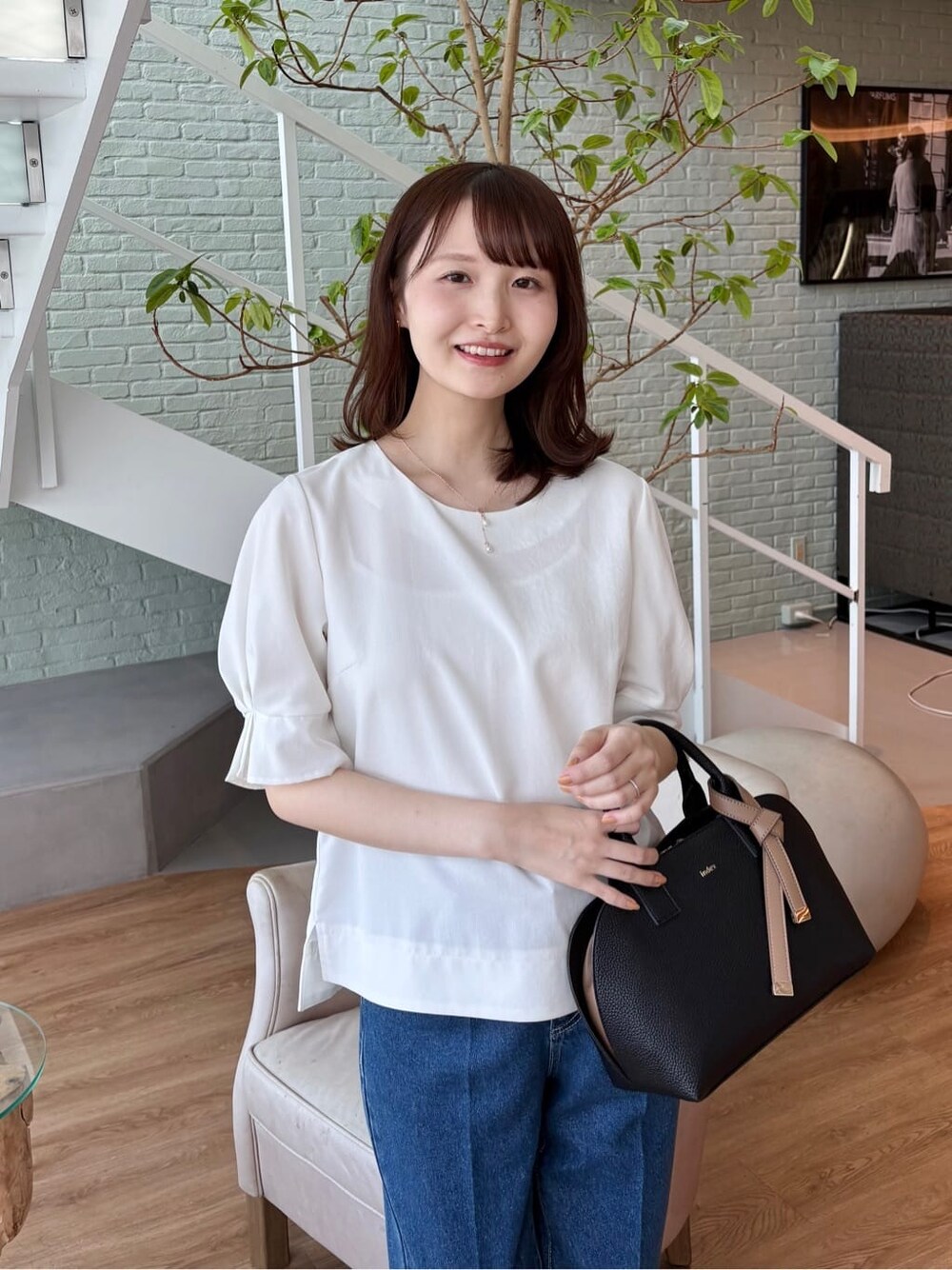 ブラック系のボストンバッグ、ブラック系のパンプス、ブルー系のその他パンツを着用したレディースの春コーディネートの6枚目の写真
