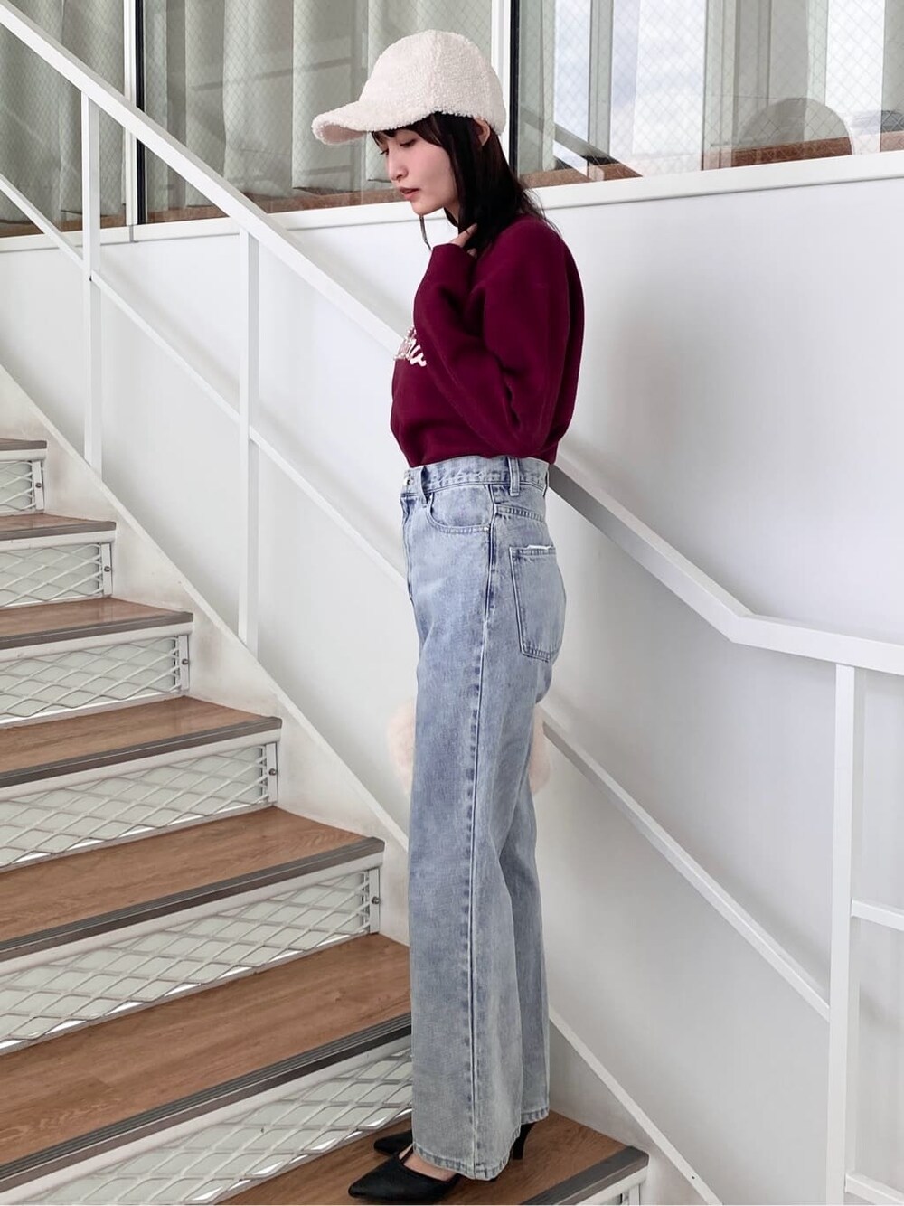 レッド系のニット/セーター、ブラック系のデニムパンツ、ホワイト系のショルダーバッグを着用したレディースの冬コーディネートの4枚目の写真