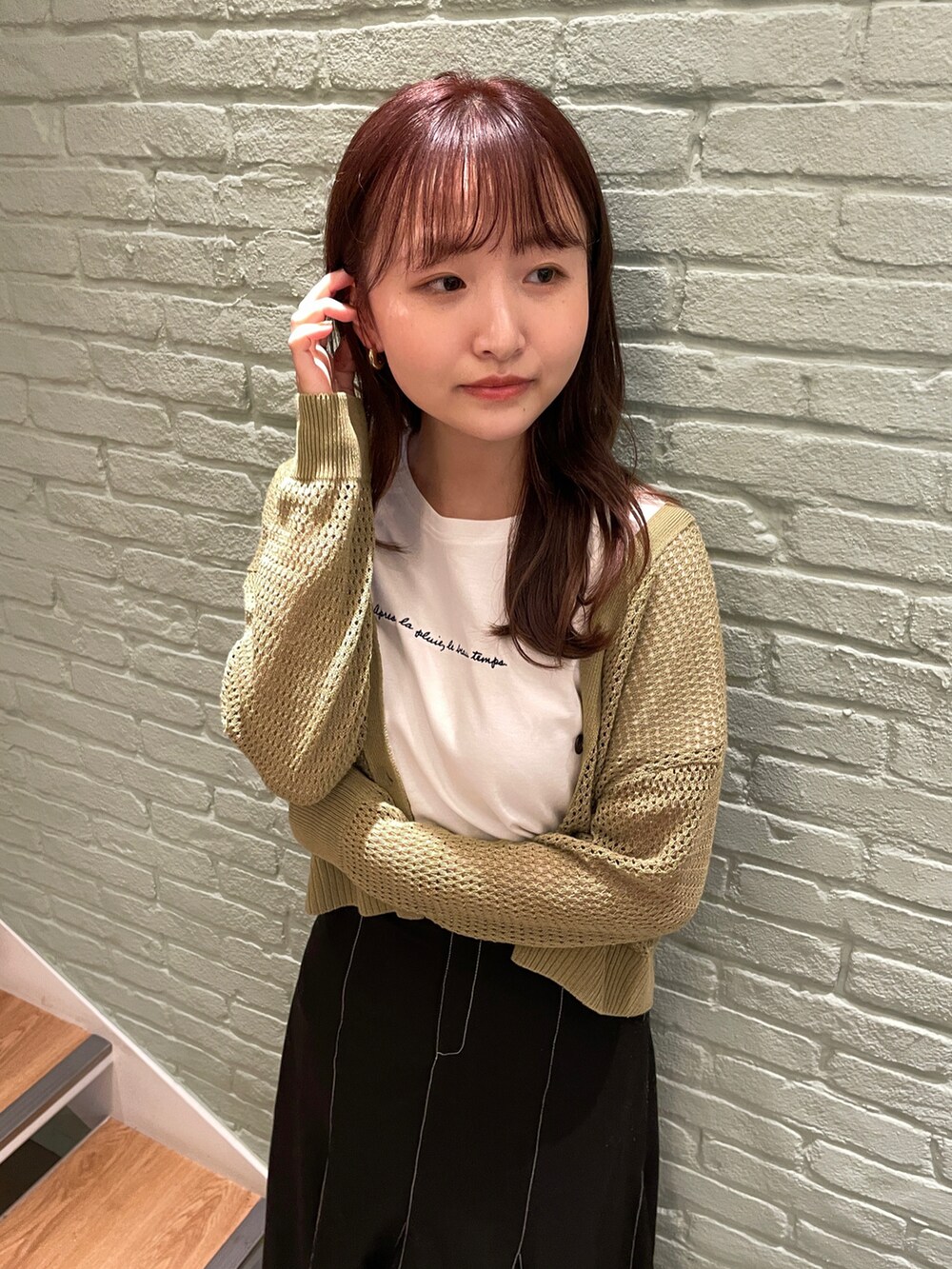 ホワイト系のTシャツ/カットソー、グリーン系のカーディガン/ボレロ、ブラック系のスカートを着用したレディースの春コーディネートの2枚目の写真