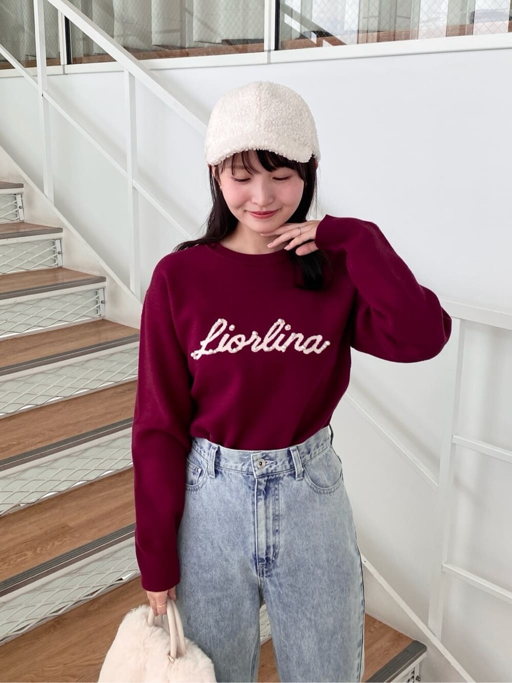 レッド系のニット/セーター、ブラック系のデニムパンツ、ホワイト系のショルダーバッグを着用したレディースの冬コーディネートの6枚目の写真
