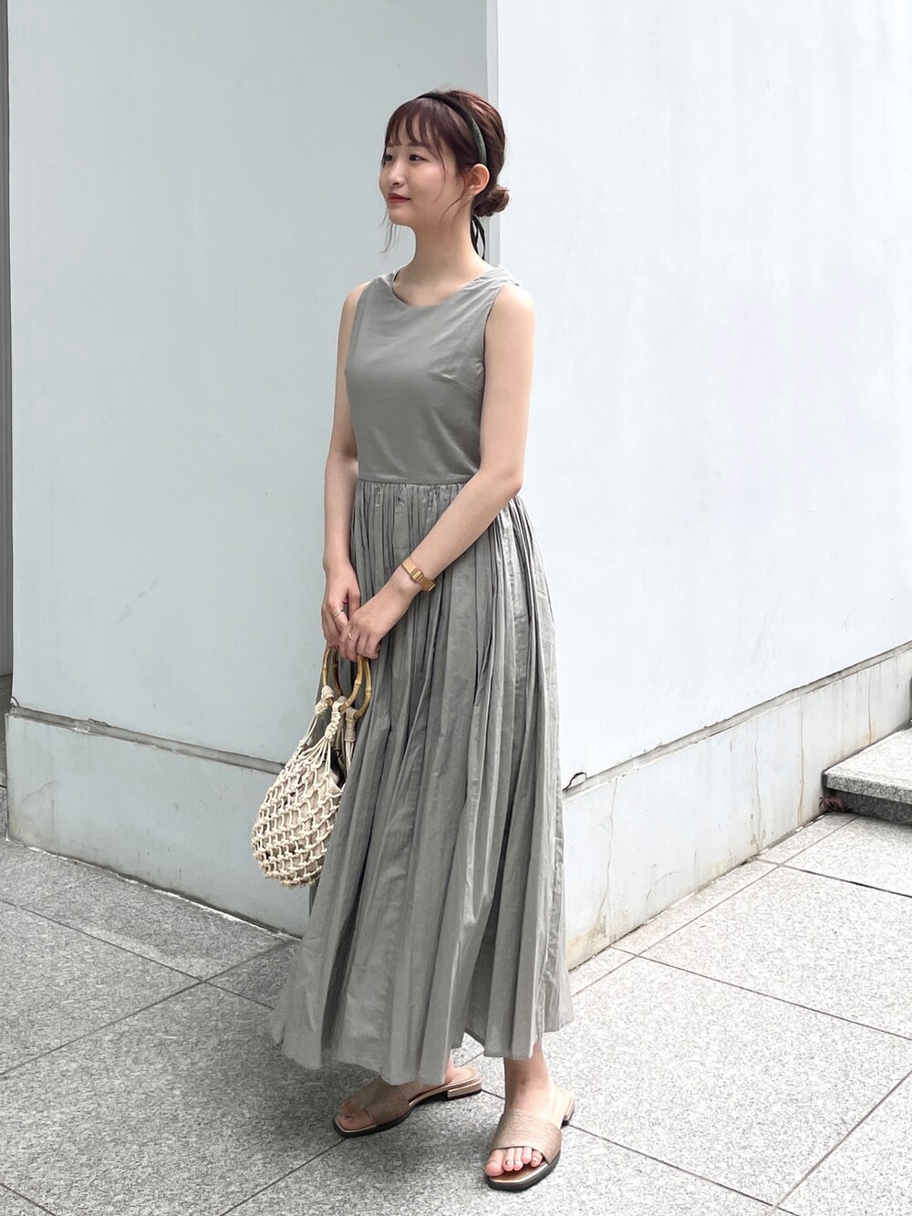 グレー系のワンピース、ゴールド系のサンダル、ベージュ系のハンドバッグを着用したレディースの夏コーディネートの2枚目の写真