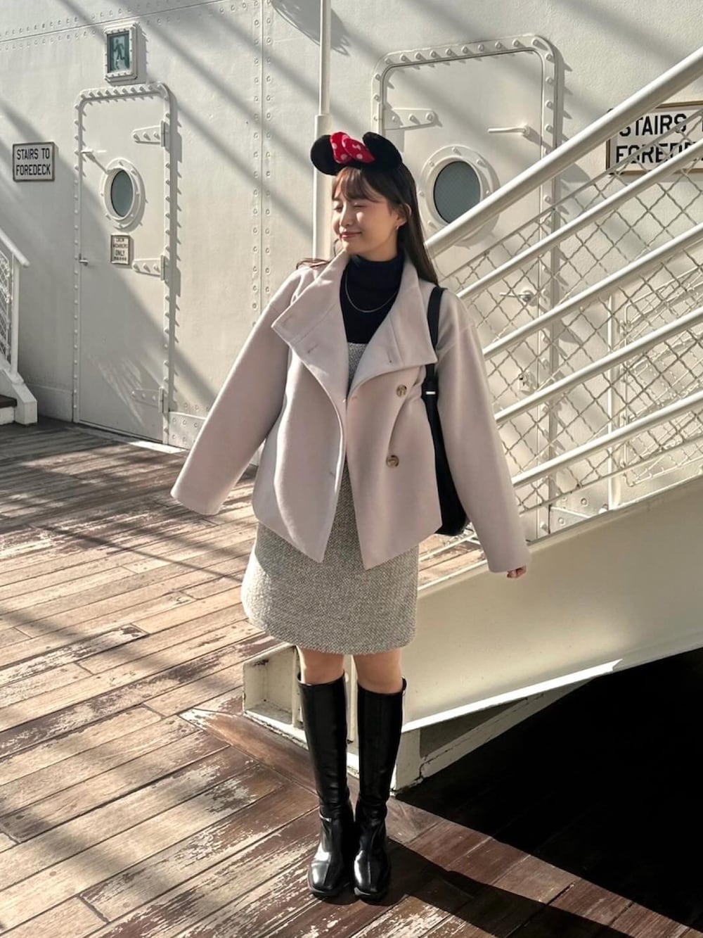 ベージュ系のその他アウター、グレー系のジャンパースカート、ブラック系のブーツを着用したレディースの冬コーディネートの2枚目の写真