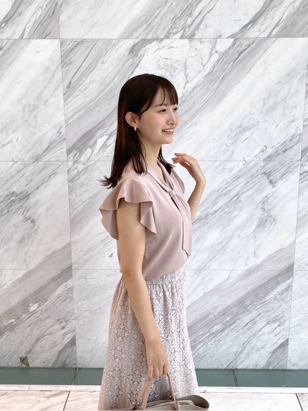 ピンク系のニット/セーター、ベージュ系のスカート、ベージュ系のトートバッグを着用したレディースの夏コーディネートの8枚目の写真
