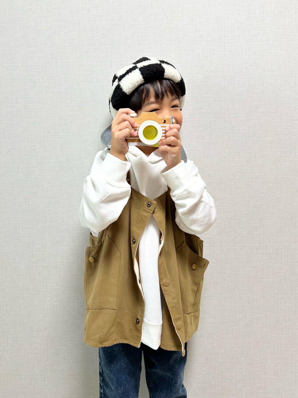 ホワイト系のパーカー、ベージュ系のベスト、ベージュ系のサンダルを着用したキッズの冬コーディネートの4枚目の写真