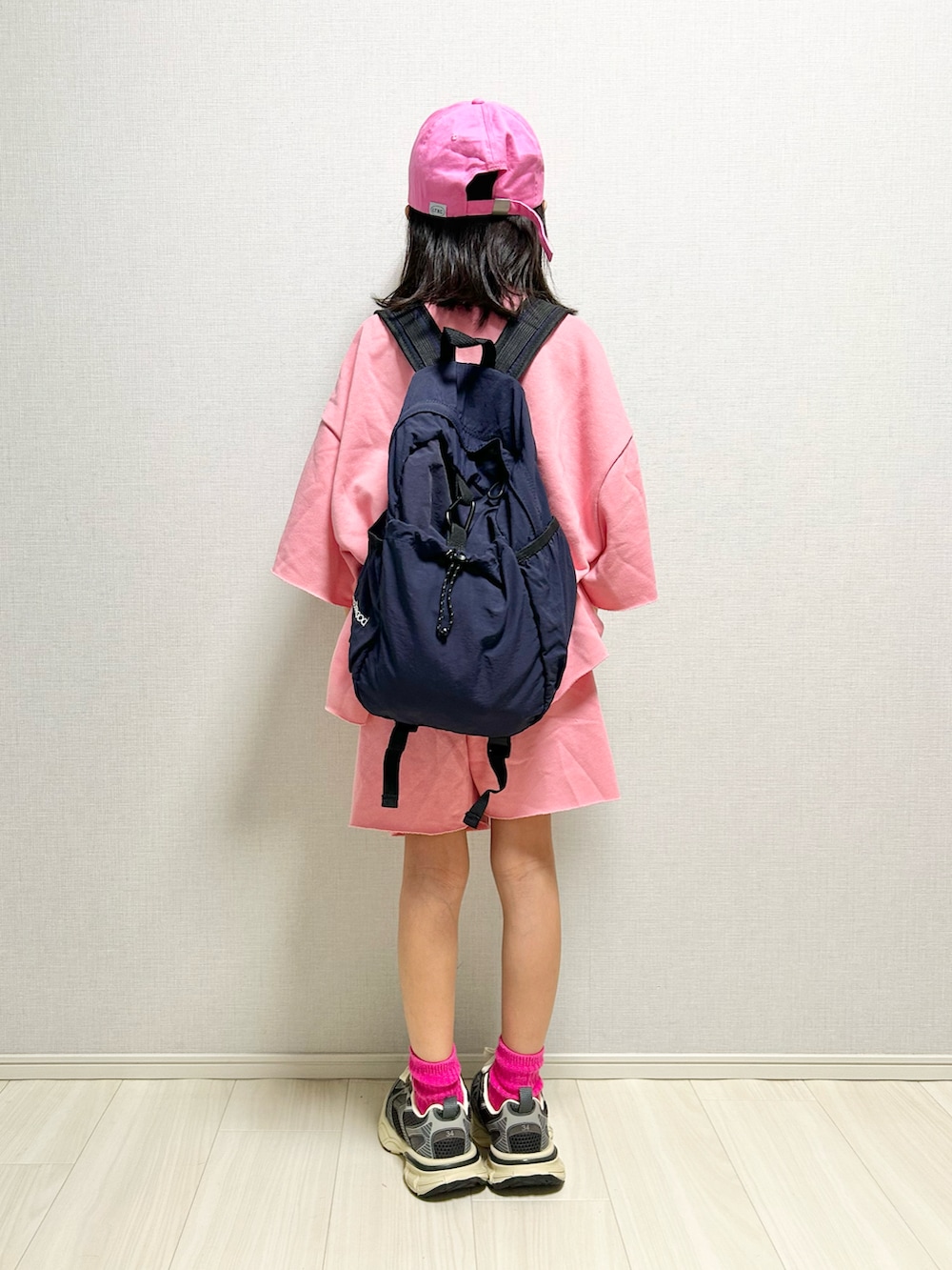 ピンク系のセットアップ、グレー系のスニーカー、ブルー系のバックパック/リュックを着用したキッズの春コーディネートの4枚目の写真