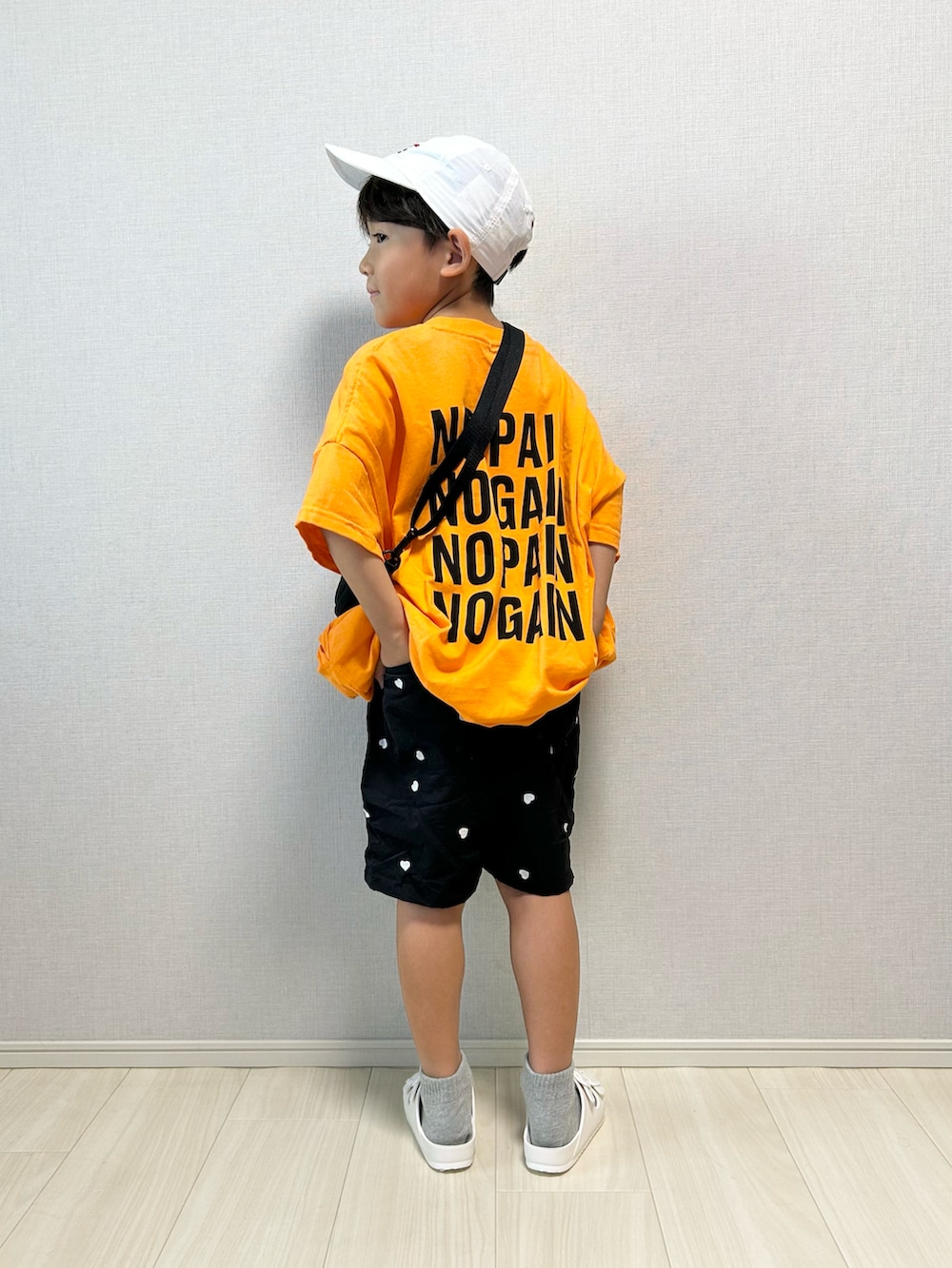 オレンジ系のワンピース、ブラック系のその他パンツ、ホワイト系のサンダルを着用したキッズの夏コーディネートの3枚目の写真