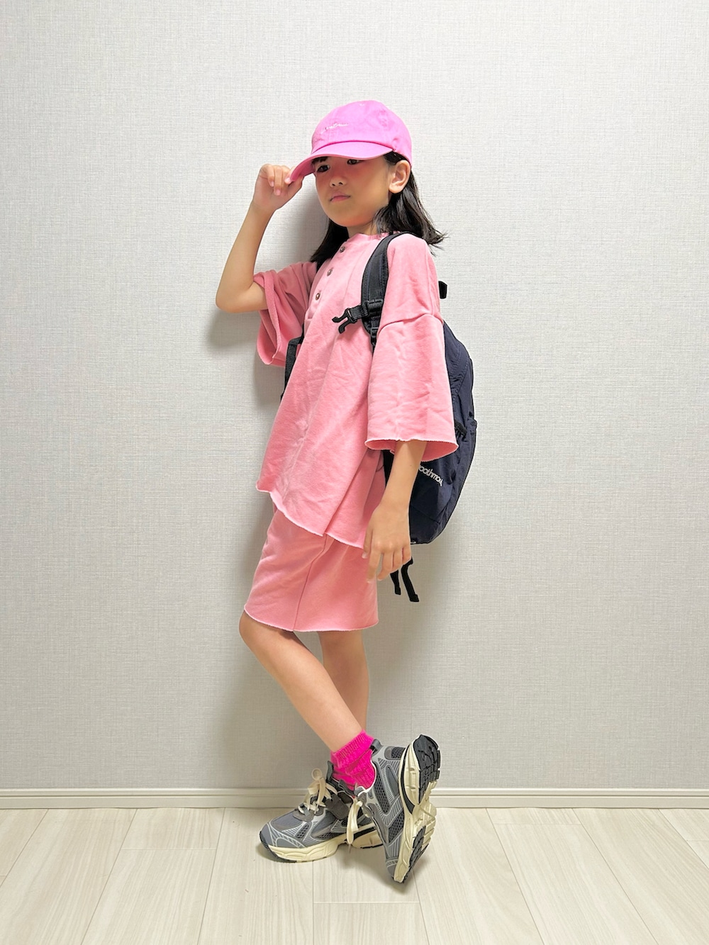 ピンク系のセットアップ、グレー系のスニーカー、ブルー系のバックパック/リュックを着用したキッズの春コーディネートの3枚目の写真