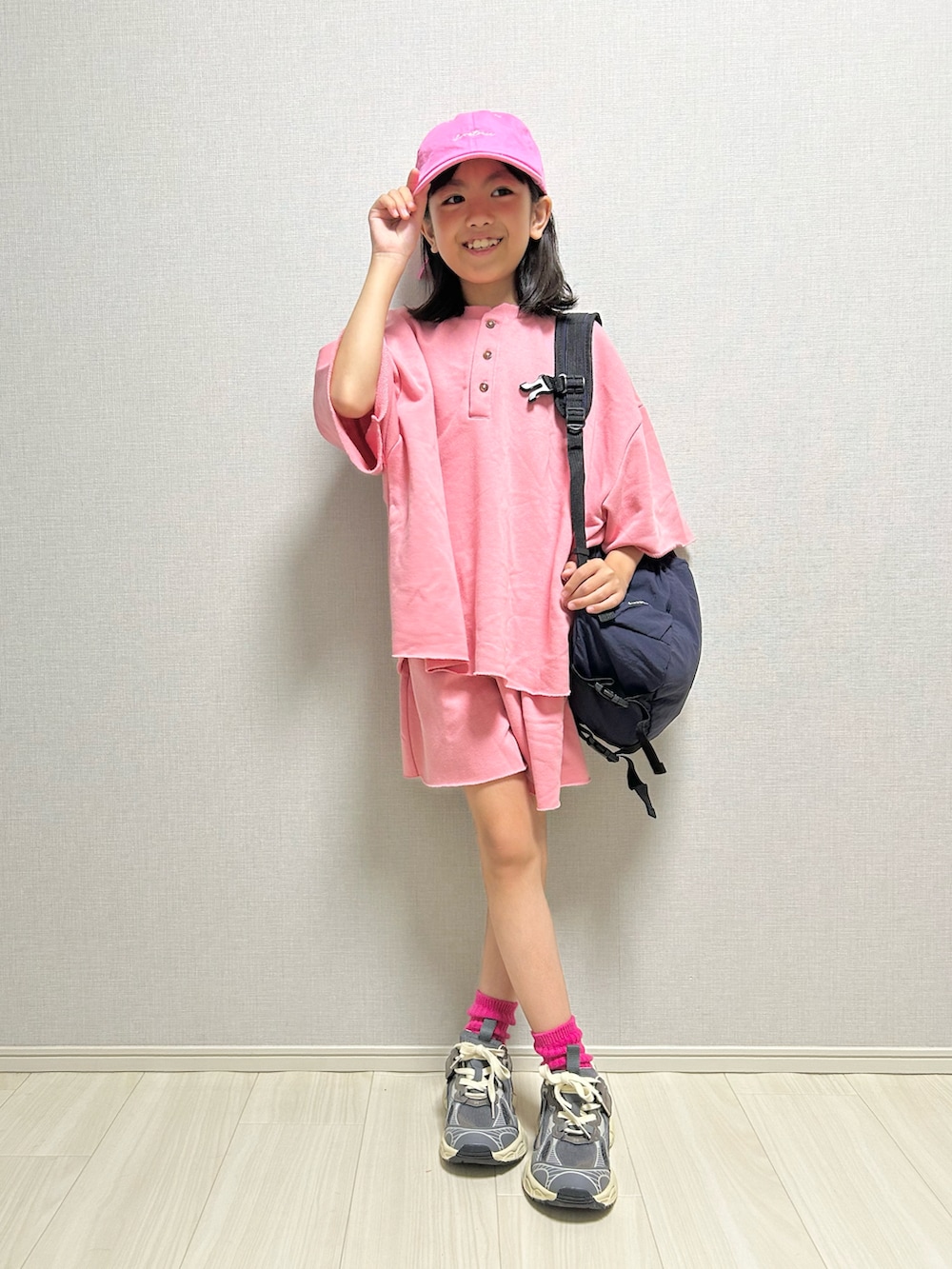 ピンク系のセットアップ、グレー系のスニーカー、ブルー系のバックパック/リュックを着用したキッズの春コーディネートの2枚目の写真