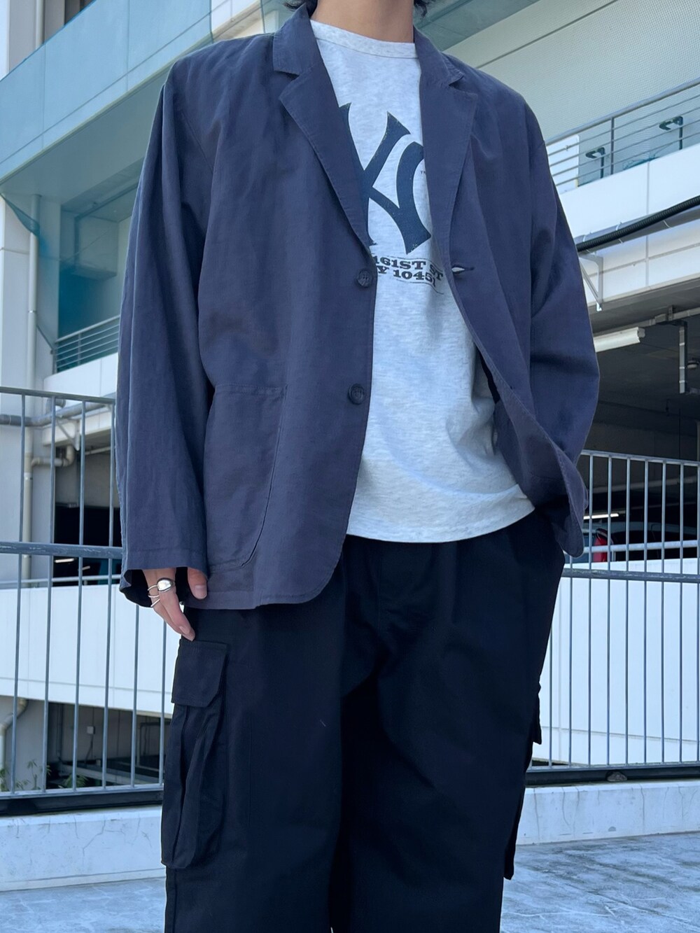 ブラック系のテーラードジャケット、グレー系のTシャツ/カットソー、ブラック系のカーゴパンツを着用したメンズの春コーディネートの3枚目の写真