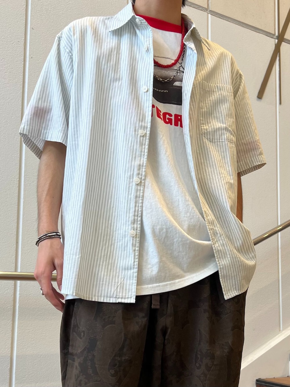 ブラウン系のスラックス、グリーン系のシャツ/ブラウス、ホワイト系のTシャツ/カットソーを着用したメンズの夏コーディネートの3枚目の写真