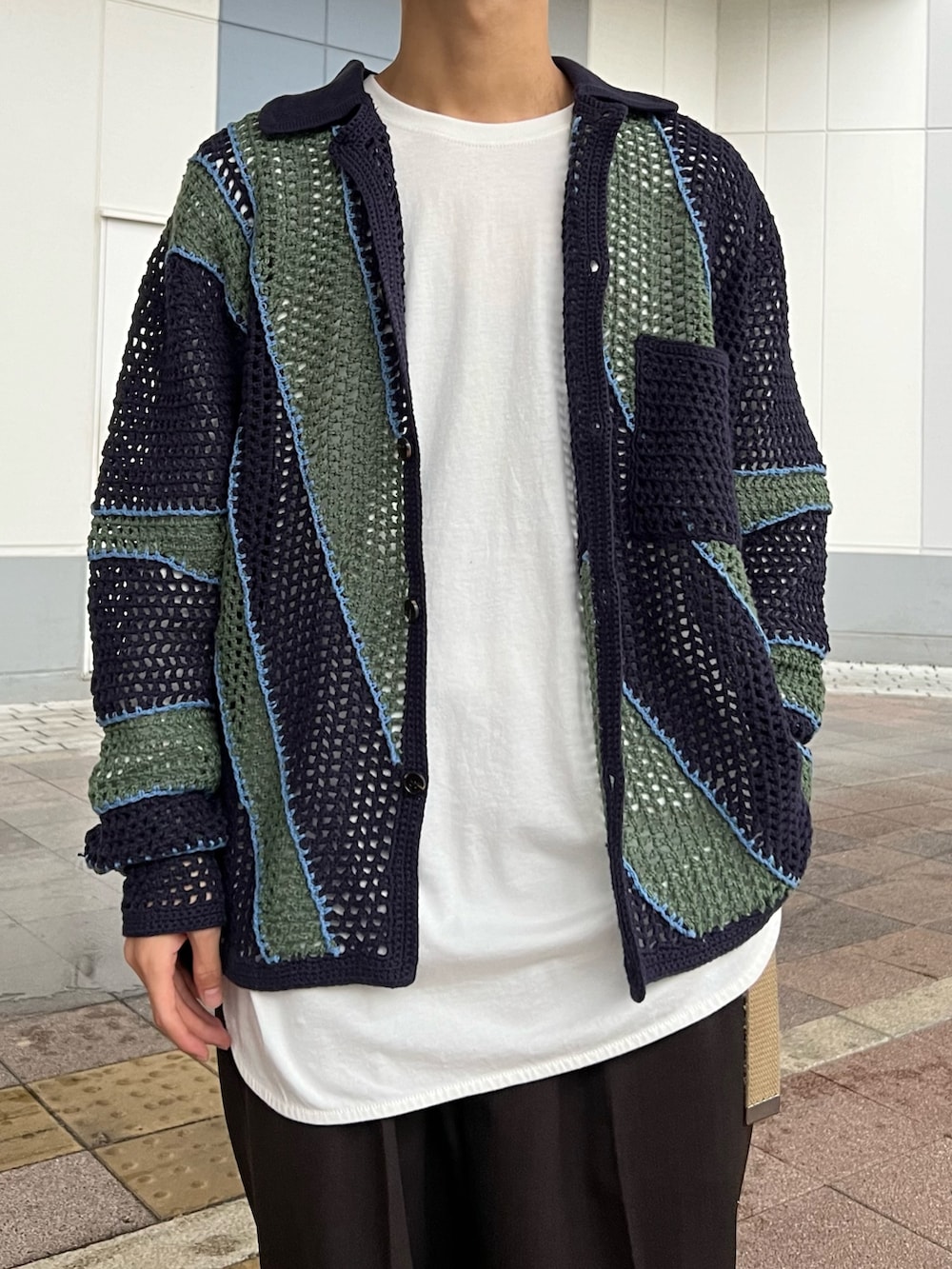 ブルー系のカーディガン/ボレロ、ホワイト系のTシャツ/カットソー、ブラウン系のスラックスを着用したメンズの秋コーディネートの2枚目の写真