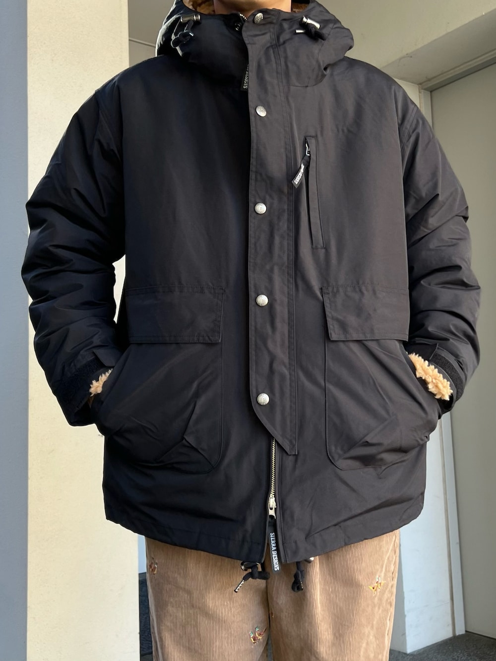 ブラック系のスニーカー、ブラック系のマウンテンパーカー、ブラウン系のその他パンツを着用したメンズの冬コーディネートの2枚目の写真