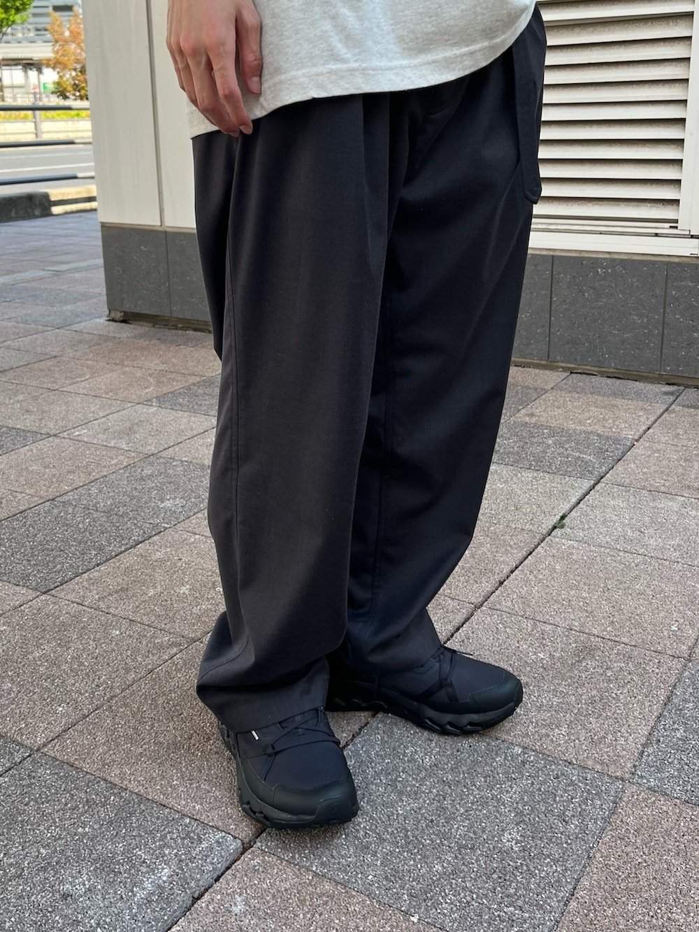 ホワイト系のTシャツ/カットソー、ブラック系のスニーカー、グレー系のスラックスを着用したメンズの春コーディネートの3枚目の写真