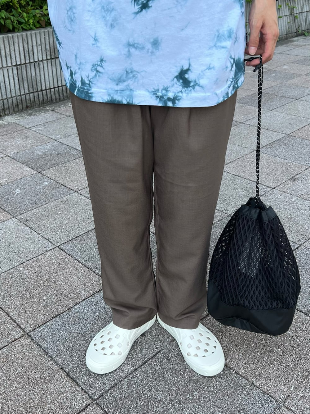 ブルー系のTシャツ/カットソー、ブラック系のバックパック/リュック、ブラウン系のスラックスを着用したメンズの夏コーディネートの4枚目の写真