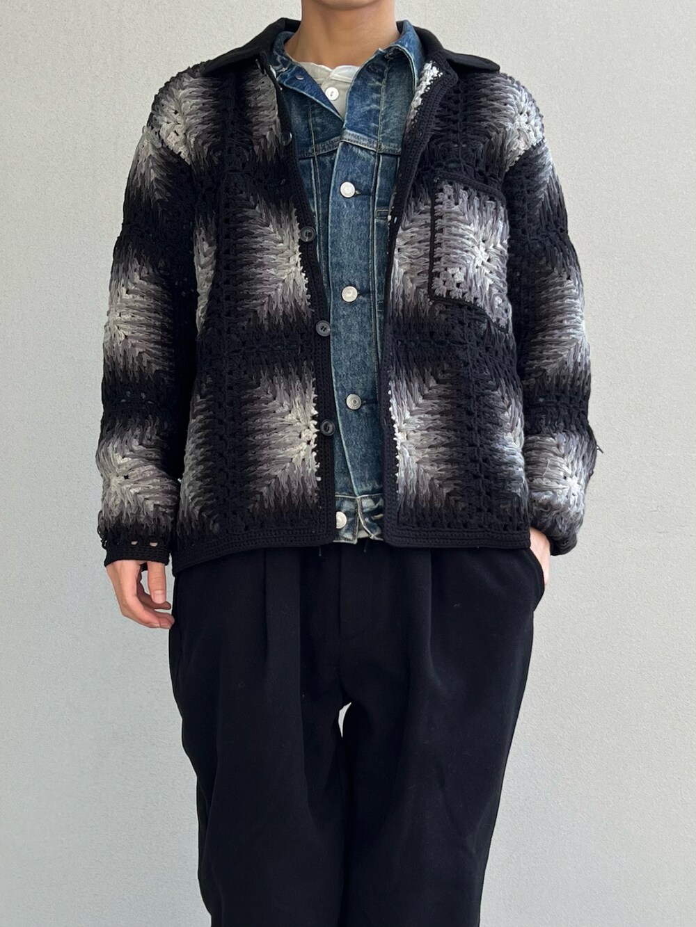 ブラック系のカーディガン/ボレロ、ブルー系のデニムジャケット、ブラック系のスラックスを着用したメンズの冬コーディネートの2枚目の写真