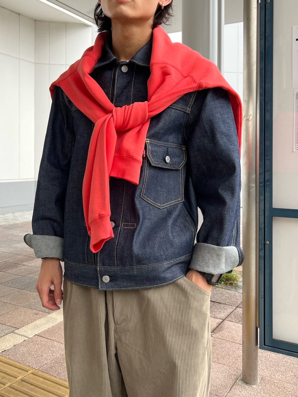 ピンク系のスウェット、ブルー系のデニムジャケット、ブラック系のサンダルを着用したメンズの秋コーディネートの3枚目の写真