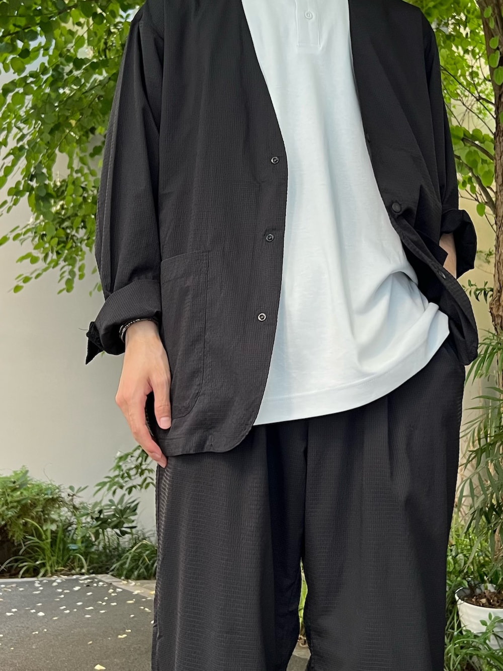 ブラック系のノーカラージャケット、ホワイト系のTシャツ/カットソー、ブラック系のスニーカーを着用したメンズの夏コーディネートの3枚目の写真