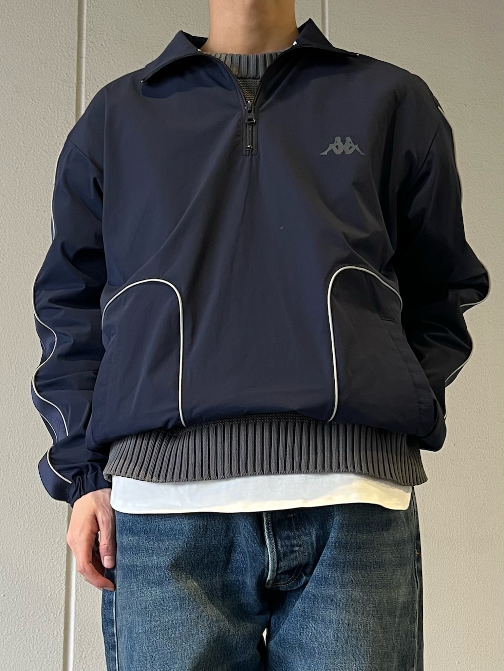 ブルー系のジャージ、グレー系のニット/セーター、ブルー系のデニムパンツを着用したメンズの春コーディネートの2枚目の写真