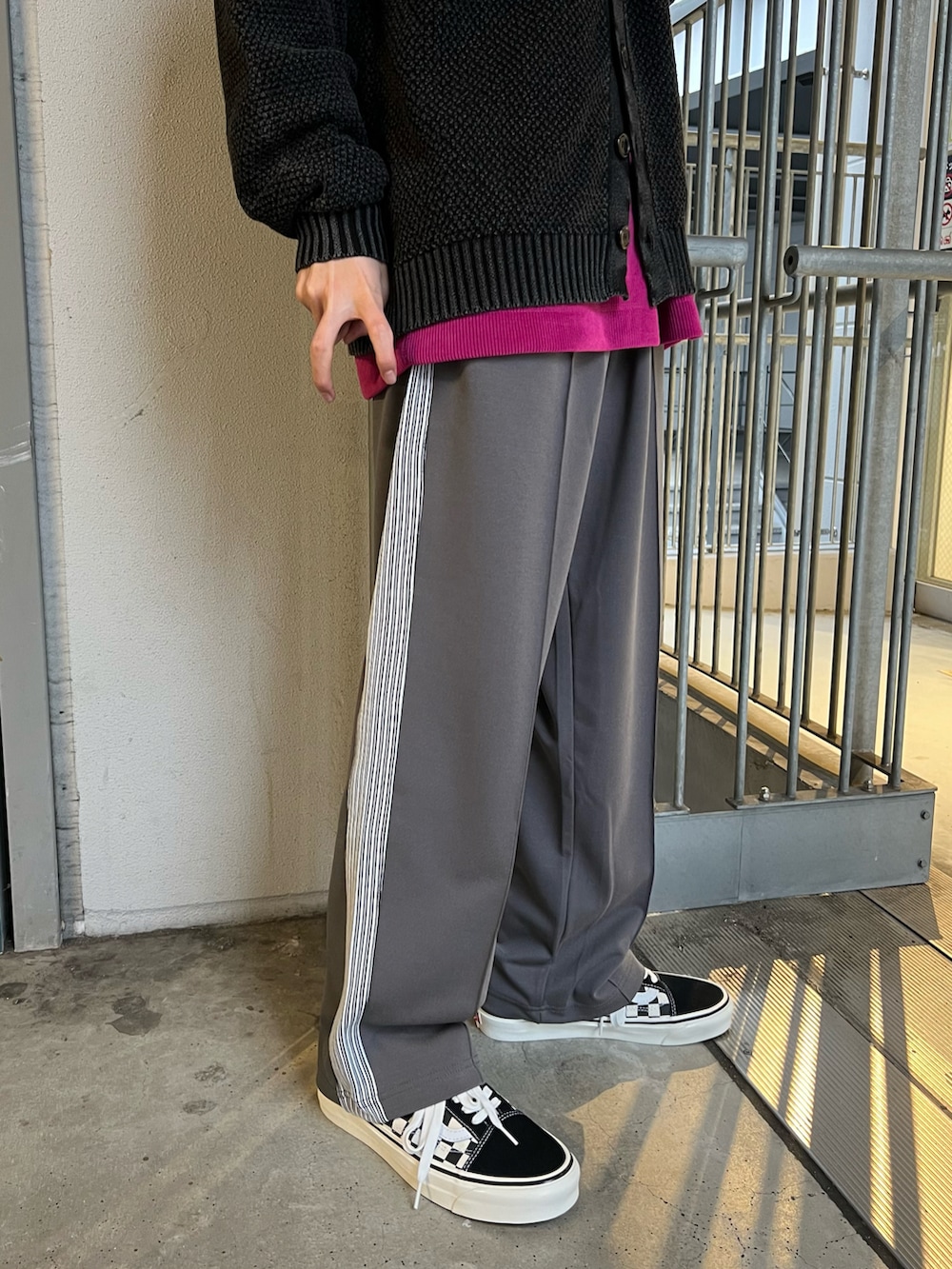 ブラック系のニット/セーター、ピンク系のTシャツ/カットソー、グレー系のその他パンツを着用したメンズの春コーディネートの2枚目の写真