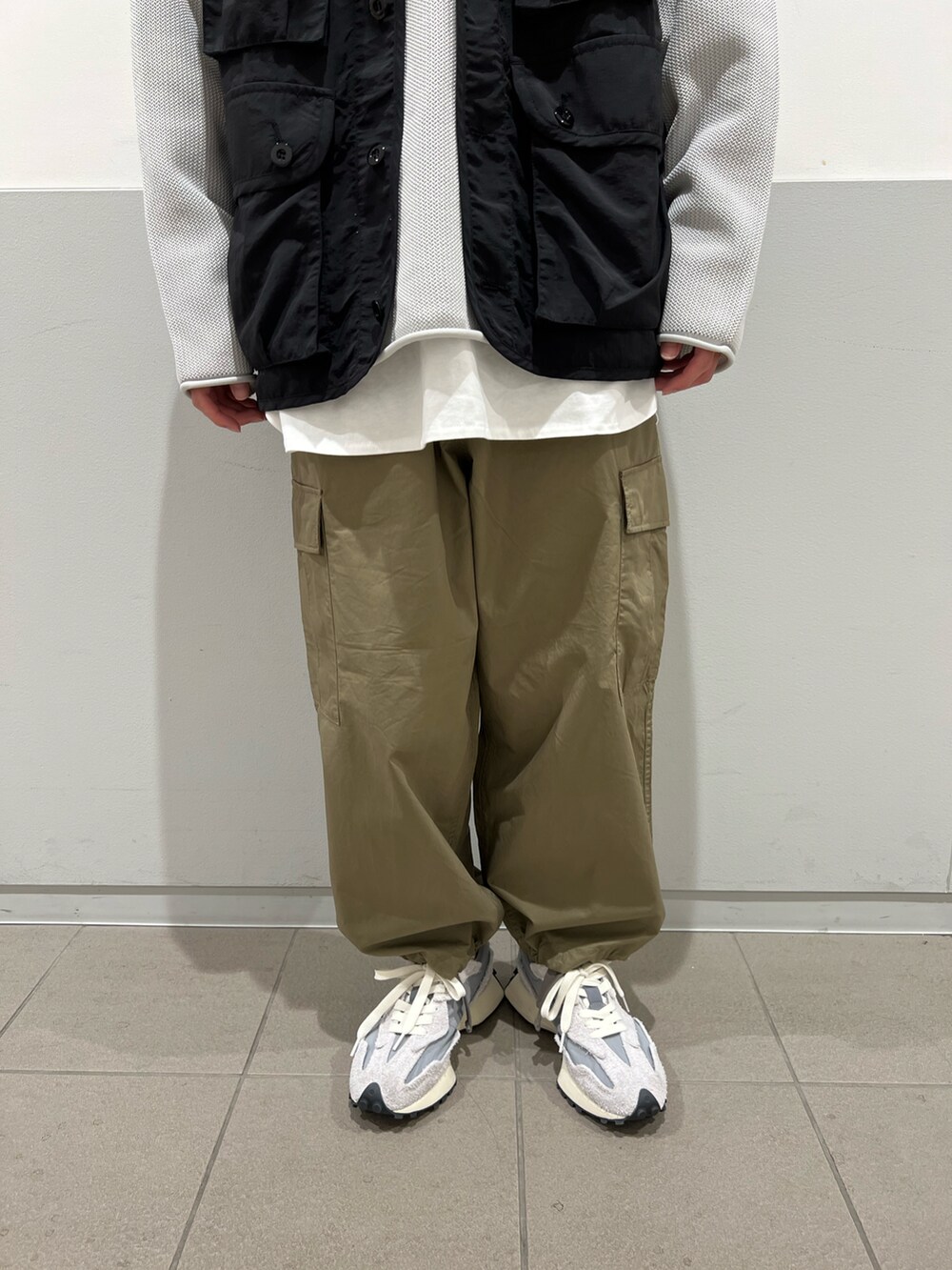 グリーン系のカーゴパンツ、グレー系のニット/セーター、ブラック系のベストを着用したメンズの春コーディネートの4枚目の写真