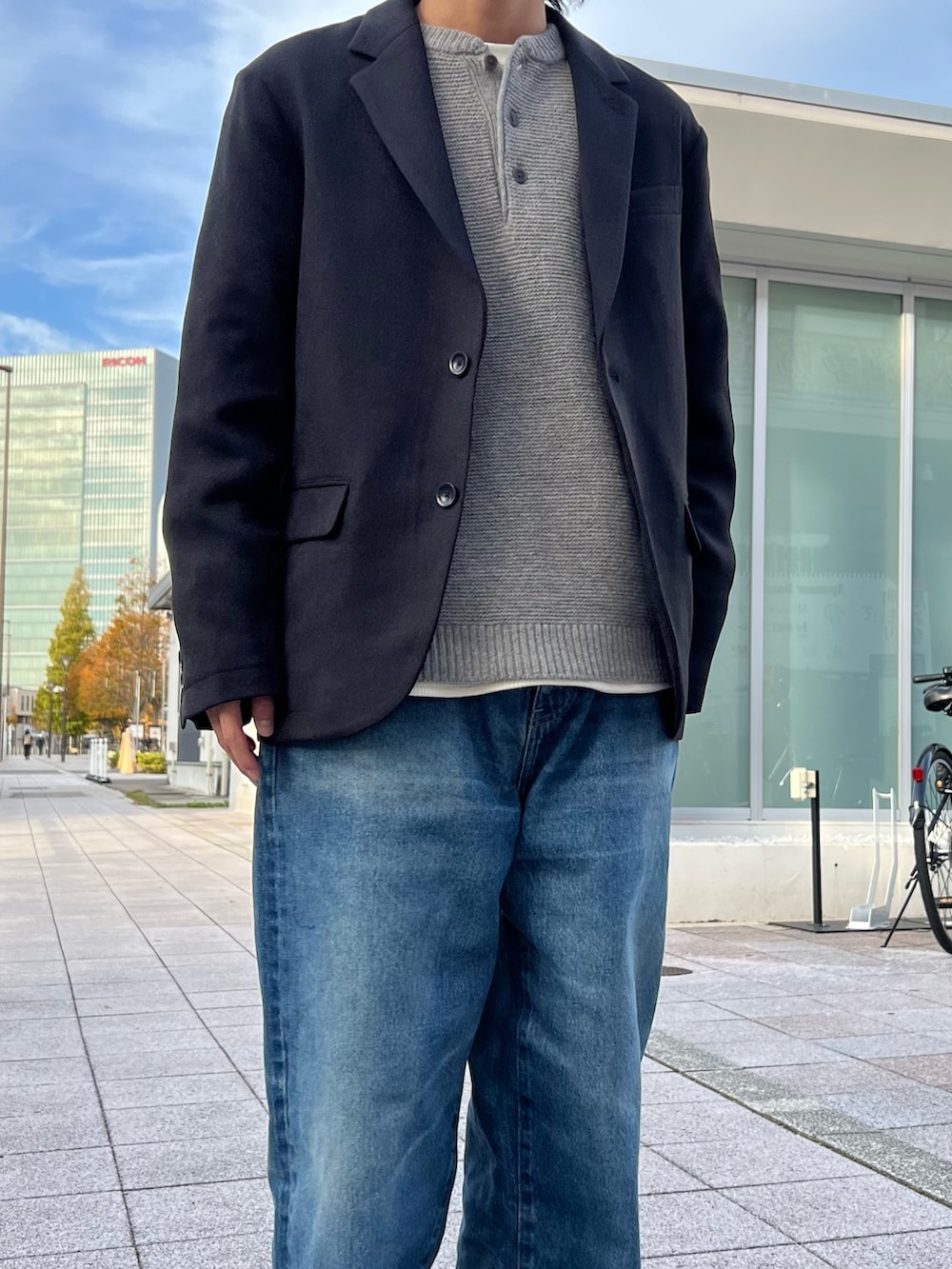 グレー系のニット/セーター、ホワイト系のTシャツ/カットソー、ブラック系のテーラードジャケットを着用したメンズの秋コーディネートの3枚目の写真