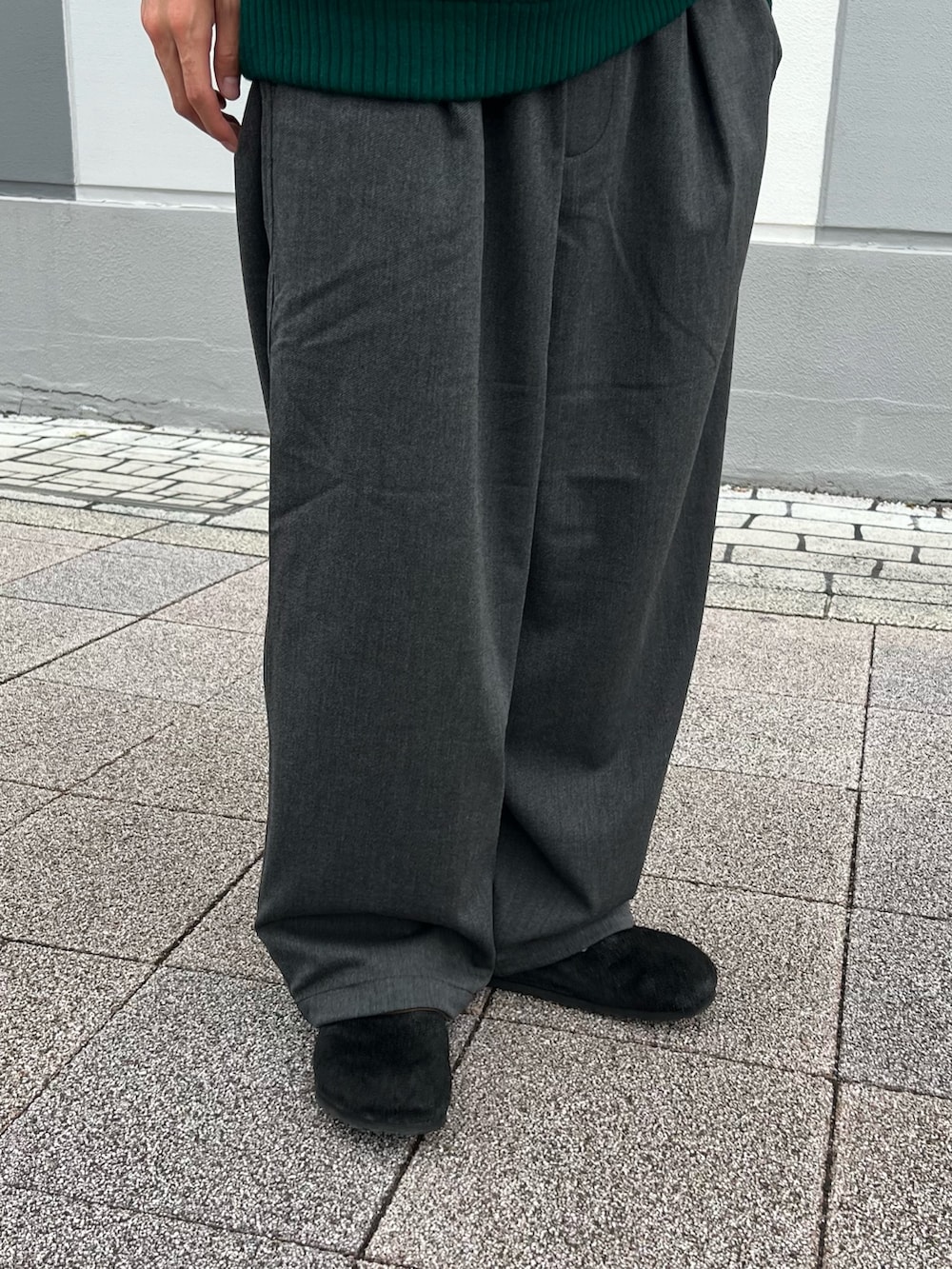 グリーン系のニット/セーター、ブラック系のサンダル、ブラック系のスラックスを着用したメンズの秋コーディネートの4枚目の写真