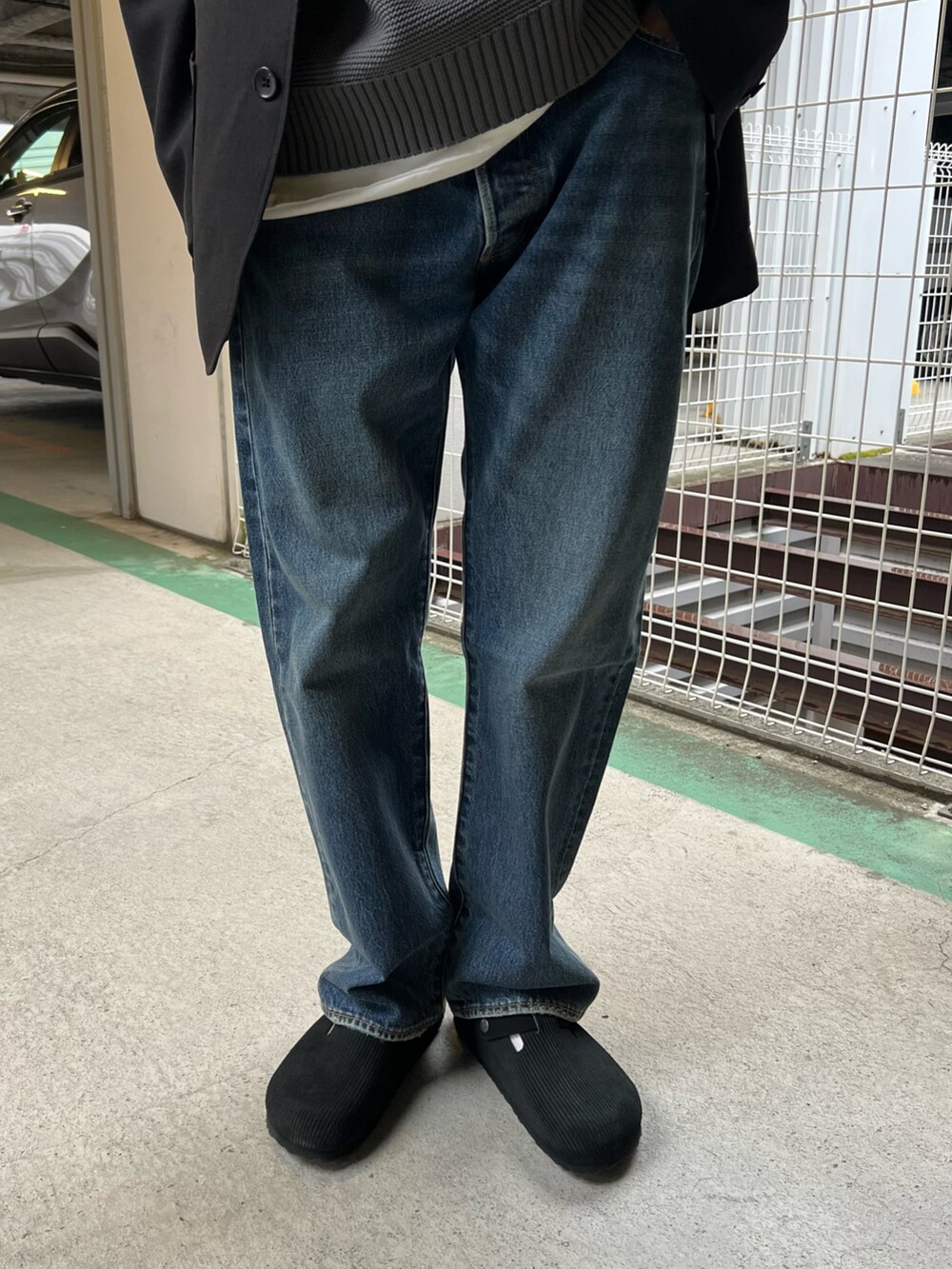 ブラック系のテーラードジャケット、グレー系のニット/セーター、ブルー系のデニムパンツを着用したメンズの春コーディネートの3枚目の写真