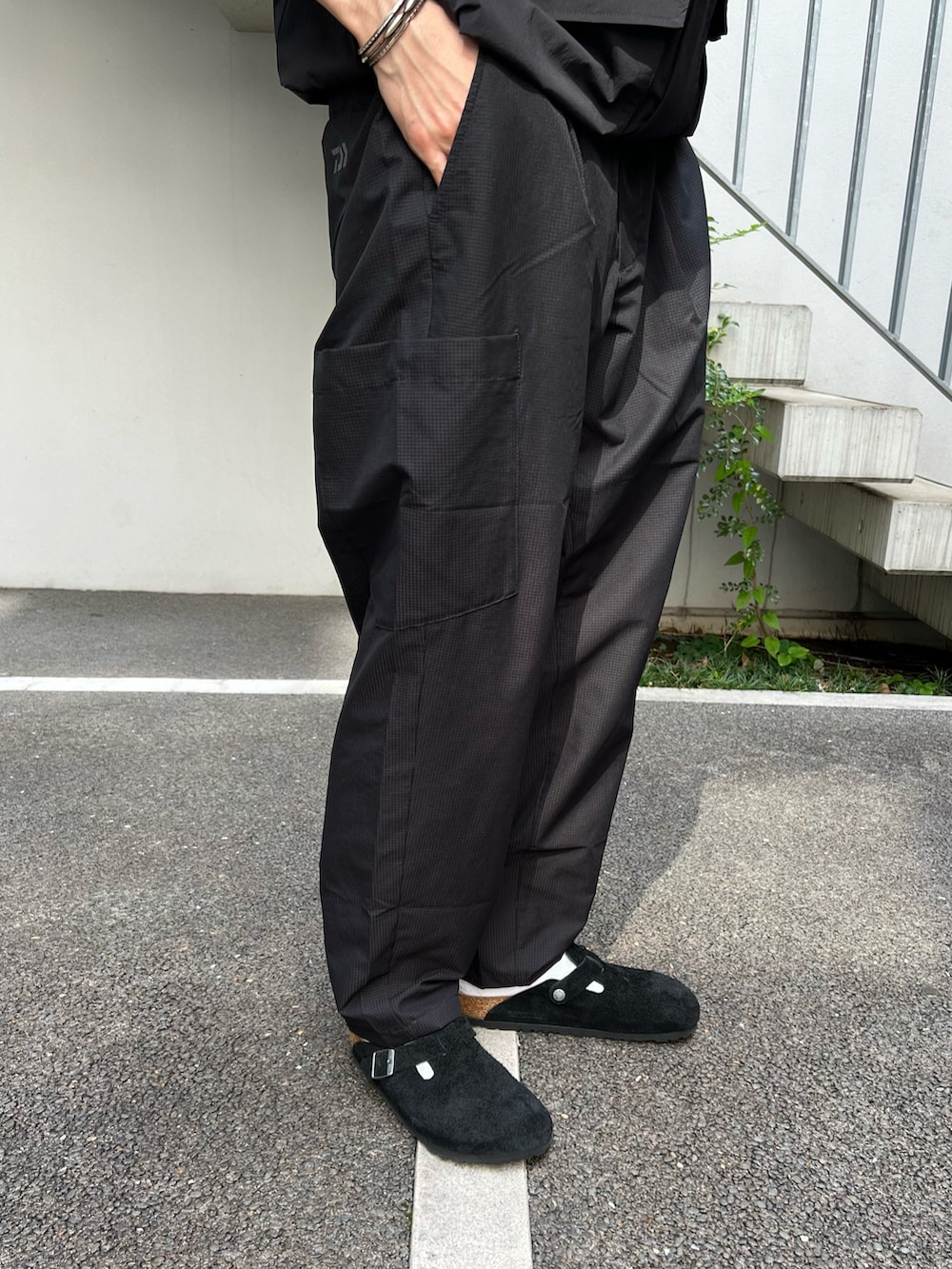 ブラック系のその他アウター、ブラック系のTシャツ/カットソー、ブラック系のスラックスを着用したメンズの春コーディネートの3枚目の写真