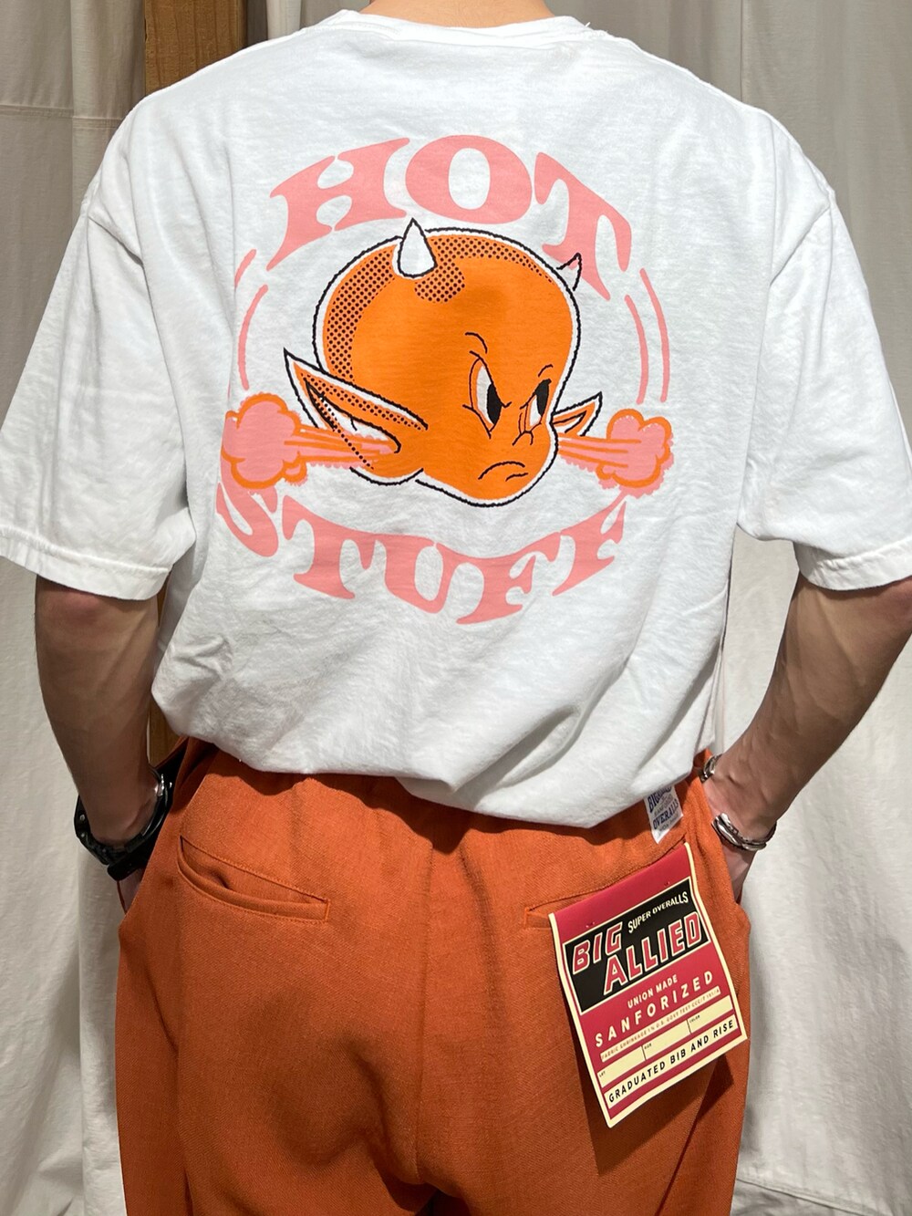 ホワイト系のTシャツ/カットソー、オレンジ系のスラックス、ブラック系のサンダルを着用したメンズの春コーディネートの2枚目の写真