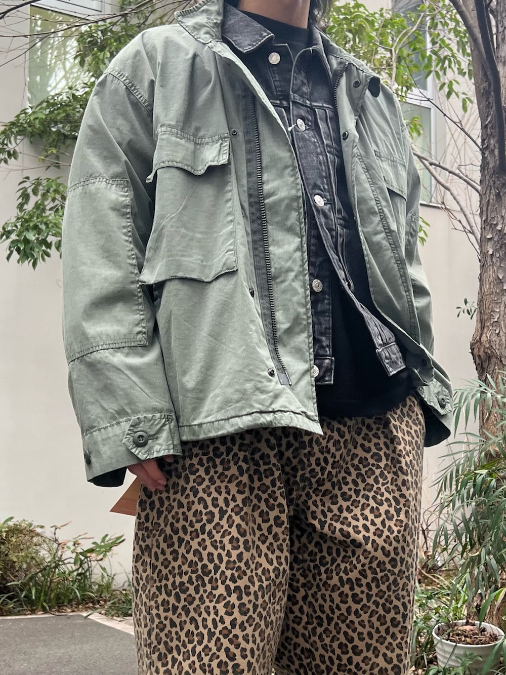 グリーン系のミリタリージャケット、ブラック系のデニムジャケット、イエロー系のチノパンツを着用したメンズの春コーディネートの3枚目の写真