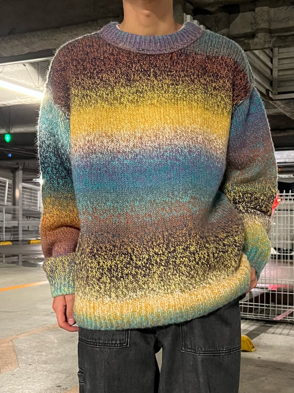 グリーン系のニット/セーター、ブラック系のデニムパンツ、ブラック系のスニーカーを着用したメンズの秋コーディネートの2枚目の写真