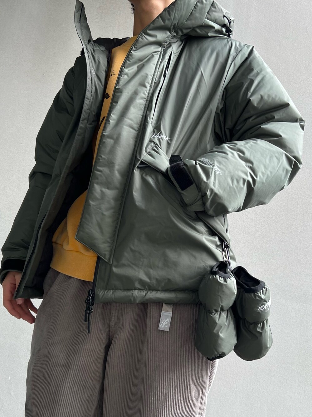 イエロー系のスウェット、グリーン系のダウンジャケット/コート、ブラウン系のスニーカーを着用したメンズの秋コーディネートの3枚目の写真