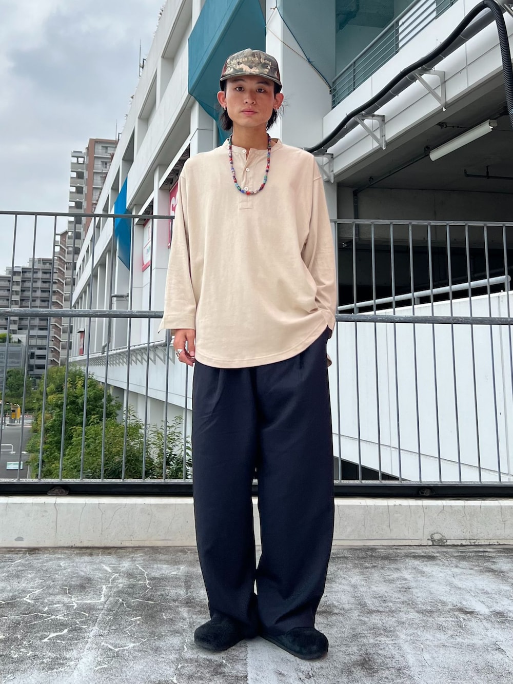 ブラック系のスラックス、ブルー系のカーディガン/ボレロ、ベージュ系のTシャツ/カットソーを着用したメンズの夏コーディネートの2枚目の写真