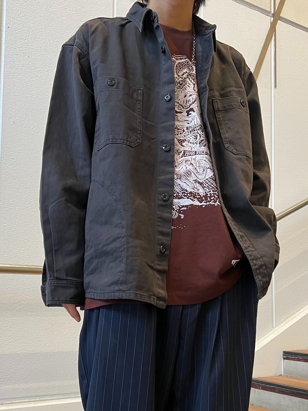 ブルー系のスラックス、ブラック系のシャツ/ブラウス、ブラウン系のTシャツ/カットソーを着用したメンズの秋コーディネートの3枚目の写真