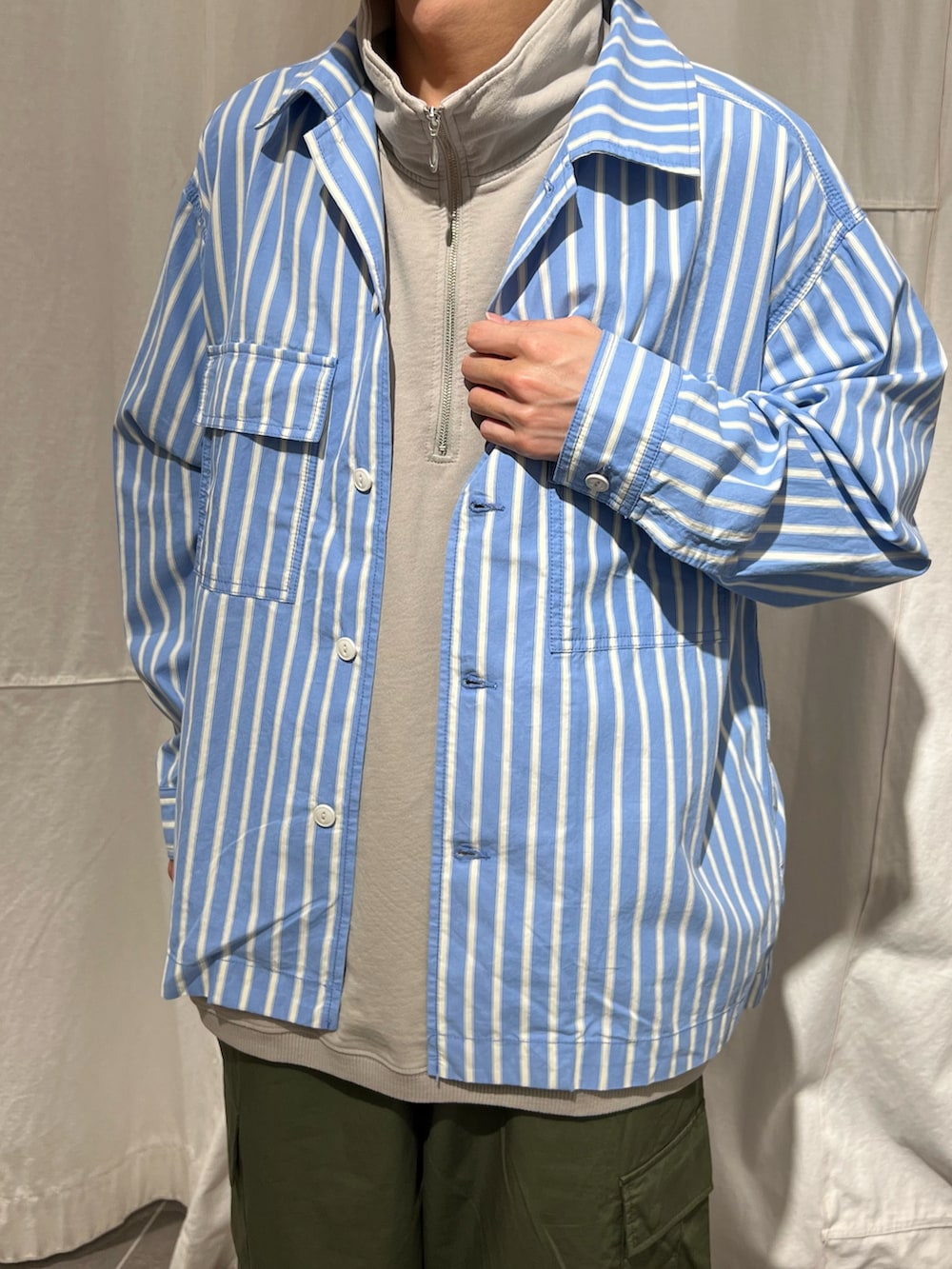 ブルー系のシャツ/ブラウス、グリーン系のカーゴパンツ、ベージュ系のTシャツ/カットソーを着用したメンズの春コーディネートの2枚目の写真