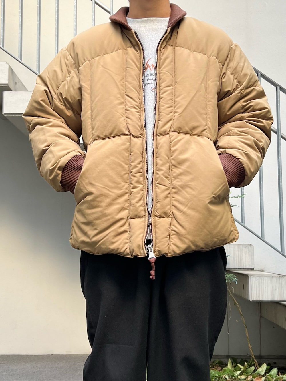 ベージュ系のダウンジャケット/コート、グレー系のスウェット、ブラック系のスラックスを着用したメンズの秋コーディネートの2枚目の写真