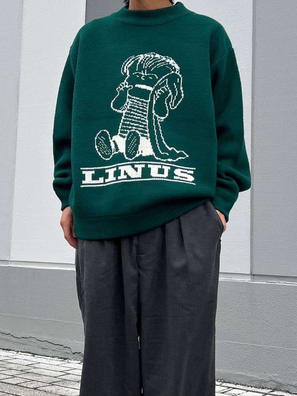 グリーン系のニット/セーター、ブラック系のサンダル、ブラック系のスラックスを着用したメンズの秋コーディネートの2枚目の写真