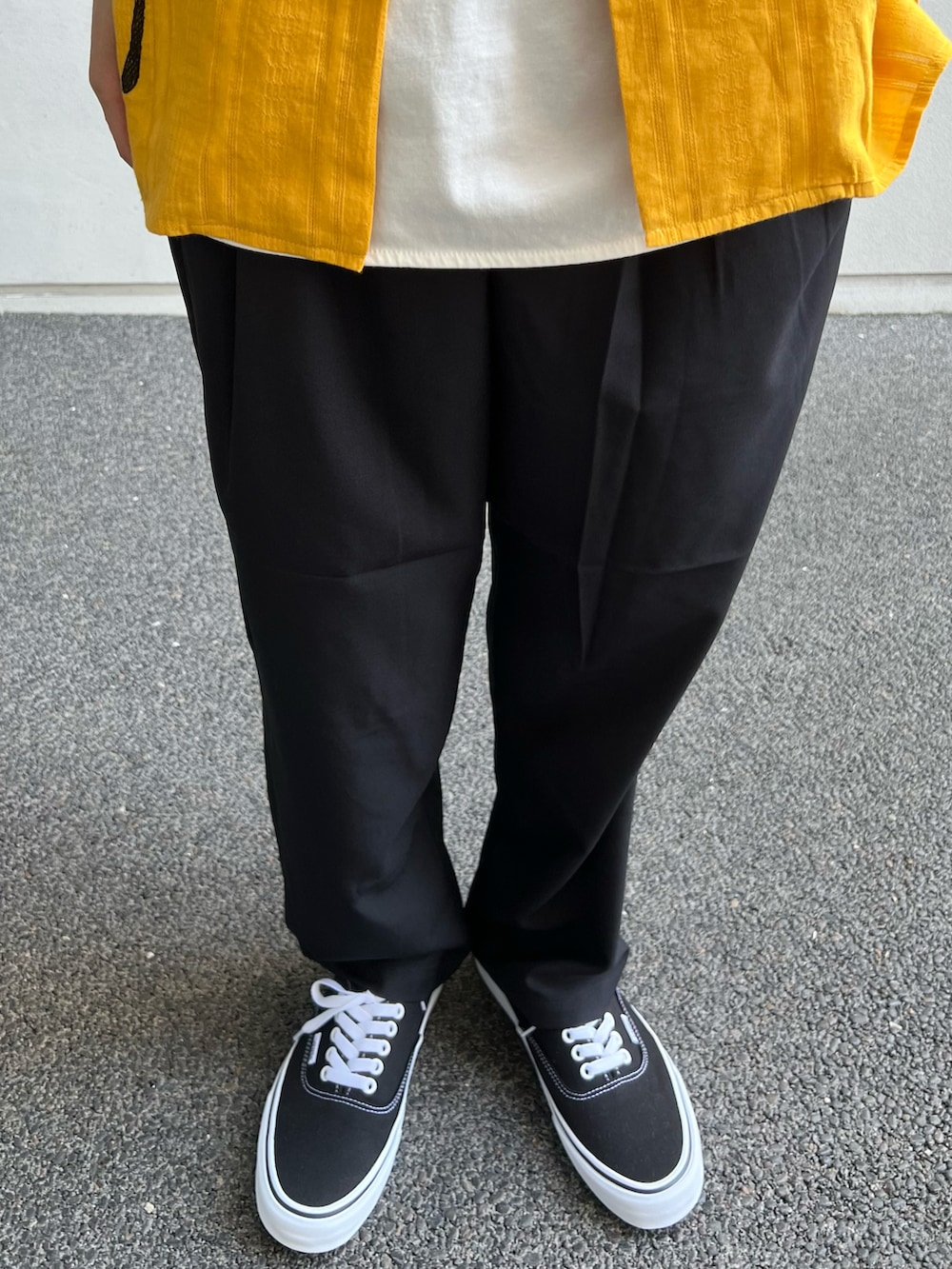 ホワイト系のTシャツ/カットソー、ブラック系のスラックス、ブラック系のスニーカーを着用したメンズの夏コーディネートの3枚目の写真