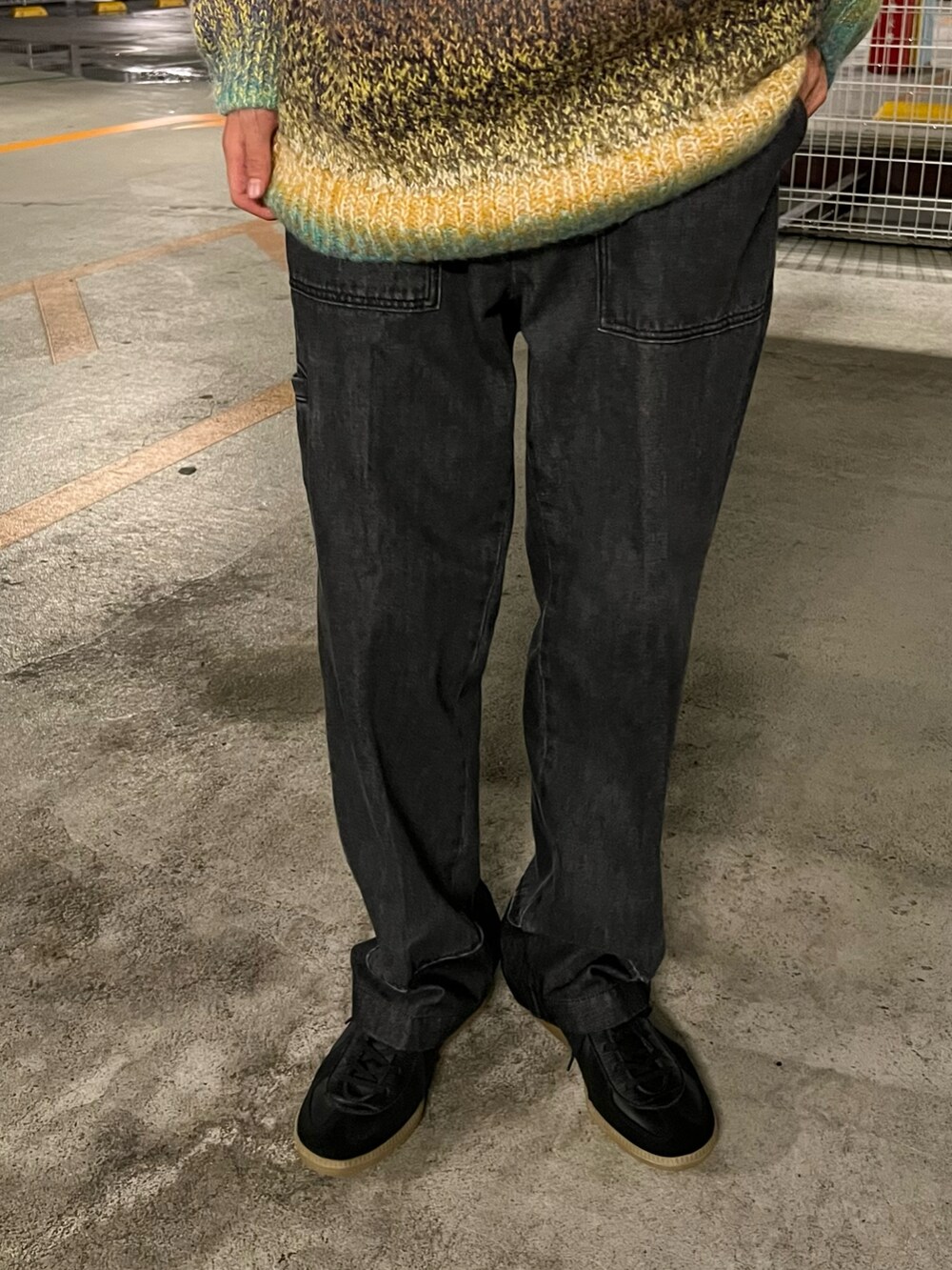 グリーン系のニット/セーター、ブラック系のデニムパンツ、ブラック系のスニーカーを着用したメンズの秋コーディネートの3枚目の写真