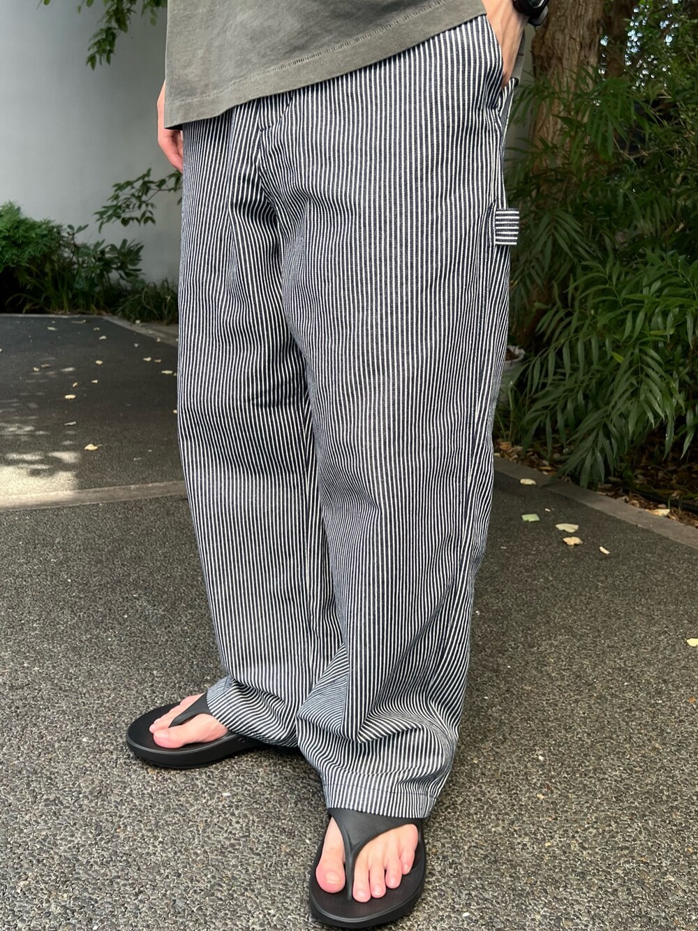 ブラック系のTシャツ/カットソー、ブルー系のデニムパンツ、ブラック系のサンダルを着用したメンズの夏コーディネートの4枚目の写真