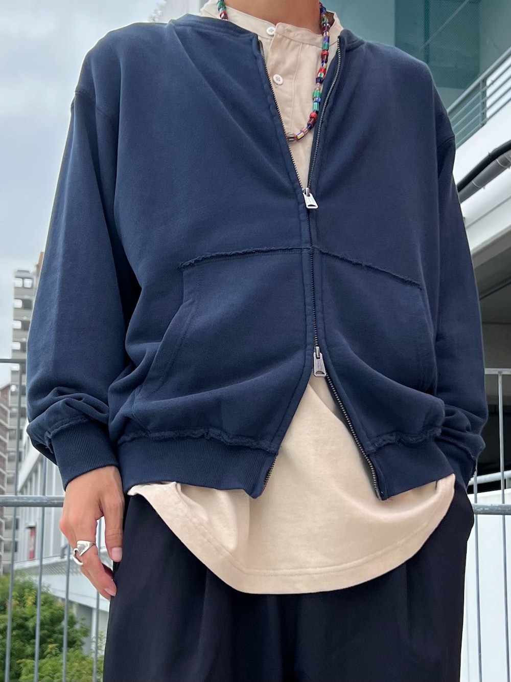ブラック系のスラックス、ブルー系のカーディガン/ボレロ、ベージュ系のTシャツ/カットソーを着用したメンズの夏コーディネートの3枚目の写真