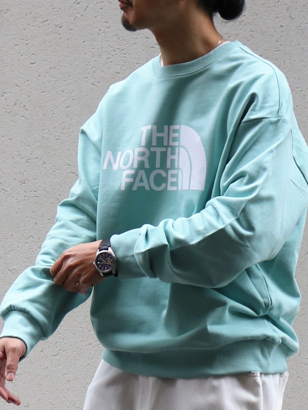 グリーン系のスウェット、ホワイト系のデニムパンツ、グレー系のリングを着用したメンズの冬コーディネートの3枚目の写真