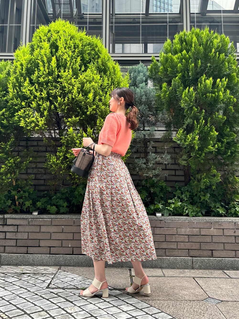 ピンク系のニット/セーター、レッド系のスカート、ホワイト系のサンダルを着用したレディースの春コーディネートの2枚目の写真